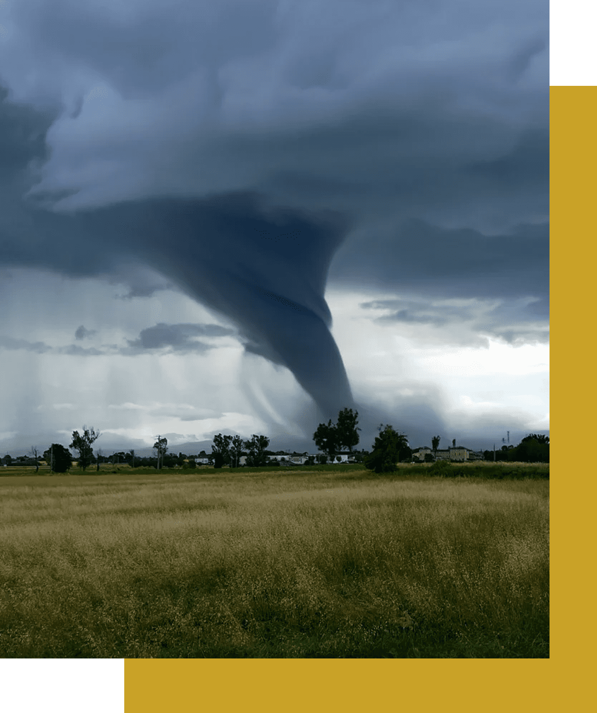A large tornado touching down in a rural area under dark storm clouds.