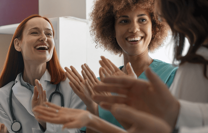 Healthcare professionals happily clapping and celebrating together.